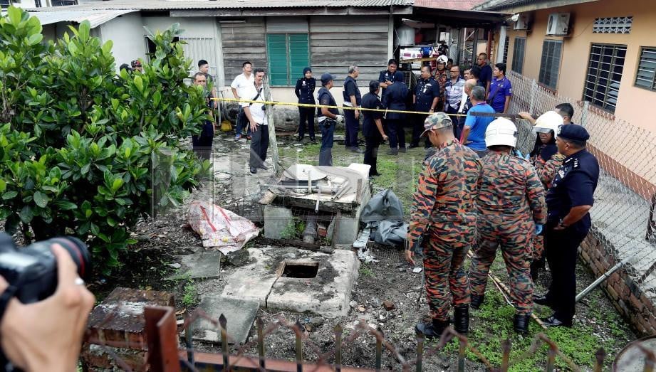 ANGGOTA bomba dan penyelamat berusaha memecahkan lantai tangki kumbahan untuk membawa keluar sebahagian anggota badan mangsa, You Su Kim, 74, yang ditanam di belakang rumah di Kampung Kanthan Baru. FOTO Muhaizan Yahya