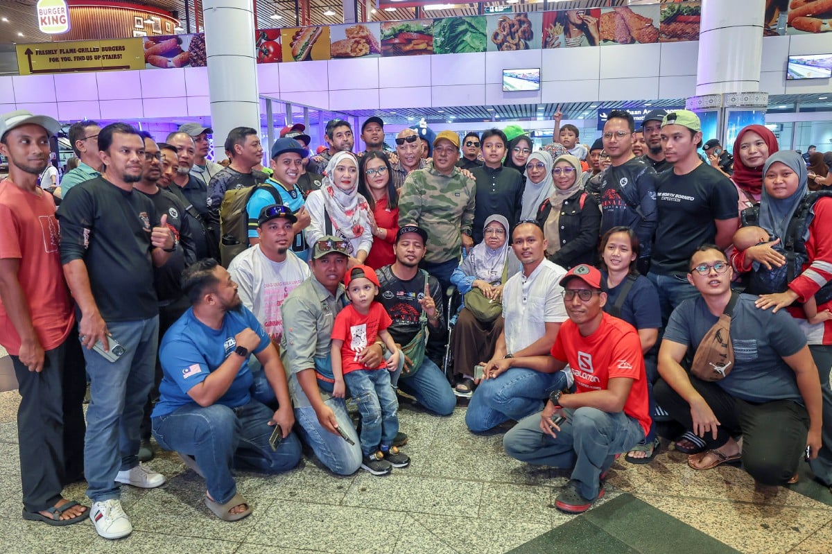ZAINUDIN (berdiri, tengah) bersama ahli keluarga dan rakan yang menyambutnya ketika tiba di KLIA Terminal 1 hari ini. FOTO Bernama 