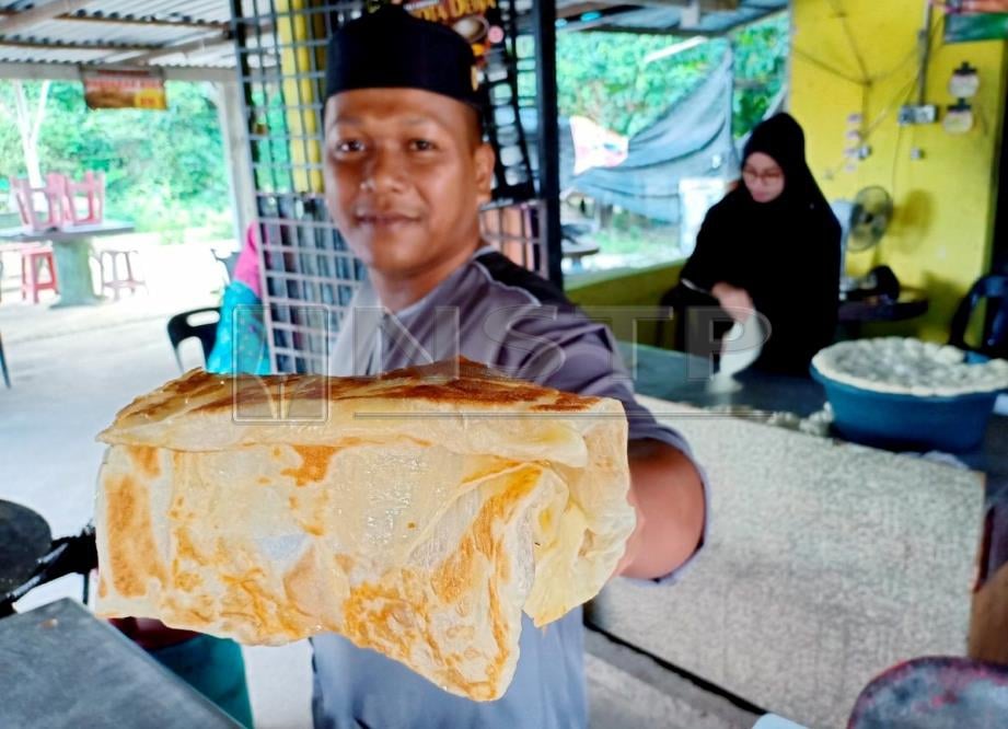 ZULFAKARUDIN menunjukkan roti canai yang dijual di kedainya sambil dibantu Nor Syuhaidah. FOTO Ahmad Rabiul Zulkifli.