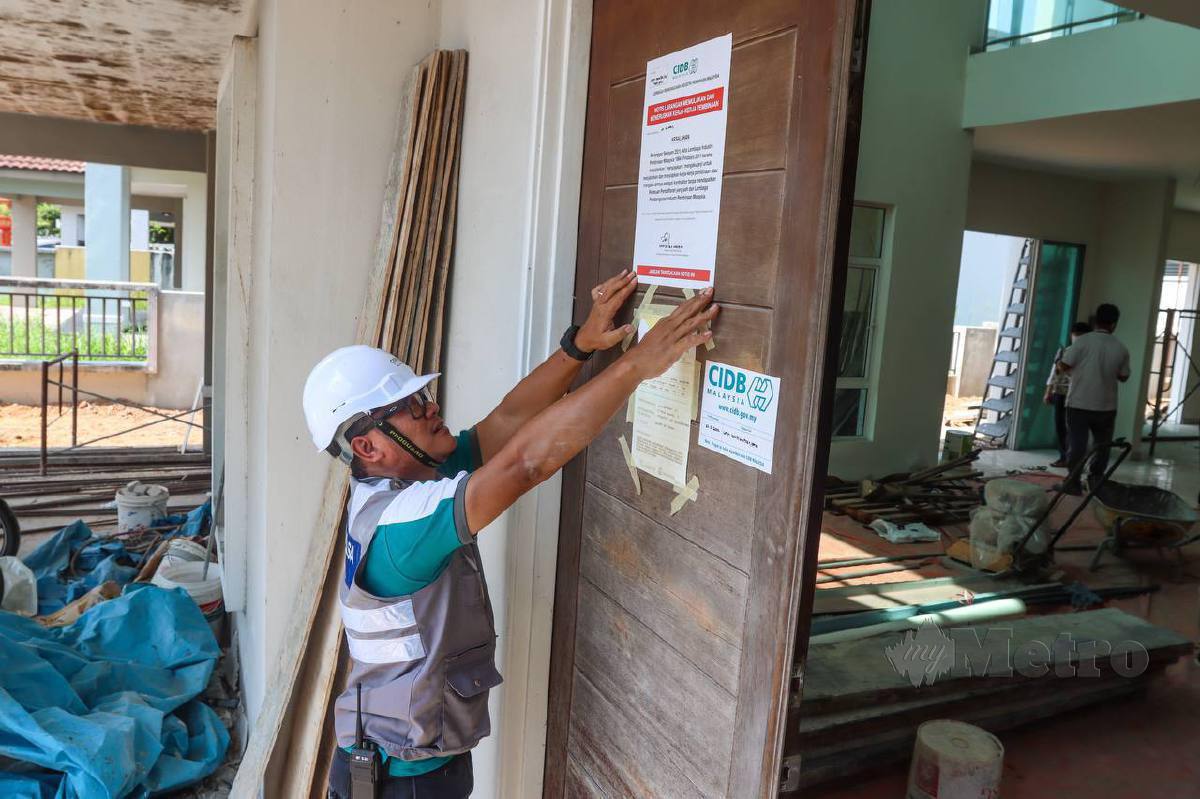 Zahidi menampal notis larangan memulakan dan meneruskan kerja-kerja pembinaan selepas melakukan pemeriksaan terhadap pekerja pembinaan ubah suai rumah ketika serbuan di sebuah rumah taman perumahan di Nibong Tebal di sini. FOTO DANIAL SAAD