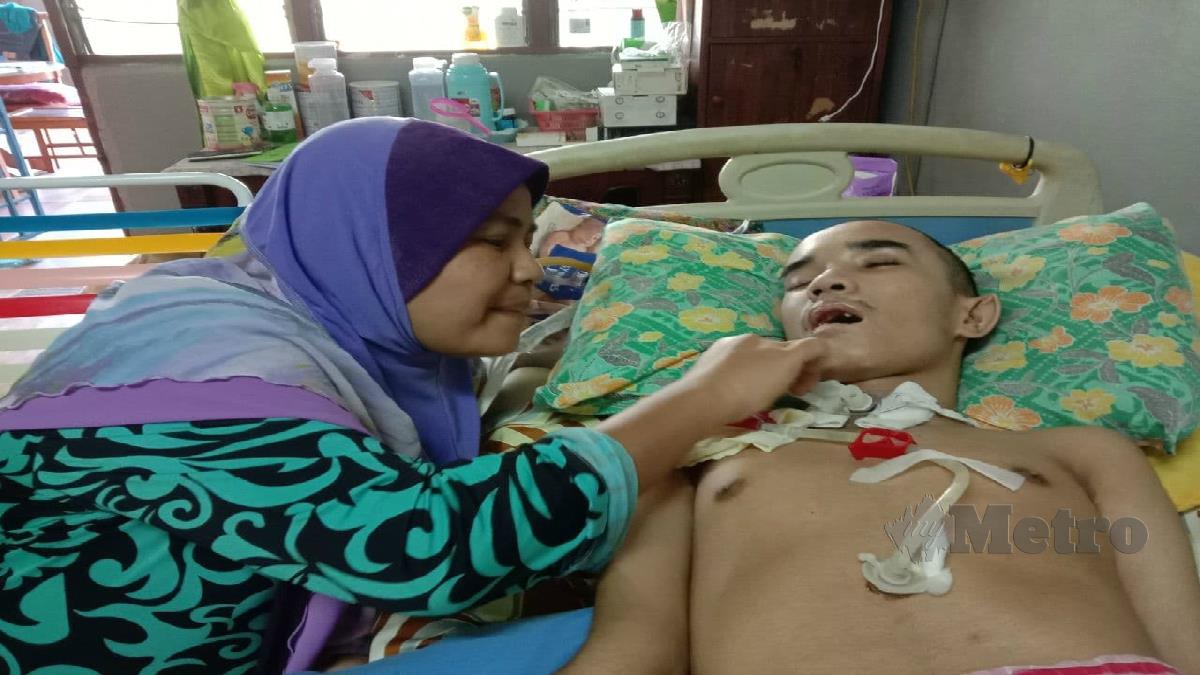 Shapidah membetulkan tiub saluran makanan anaknya Mohd Zaki yang koma akibat kemalangan jalan raya sejak tiga tahun lalu. FOTO Adnan Ibrahim