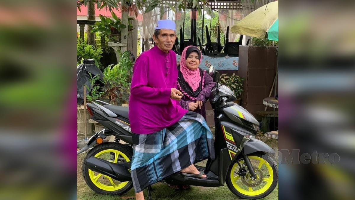 BAHARIN bersama isteri mengambil gambar kenangan dengan motosikal baharu. FOTO ihsan Rohaida Baharin
