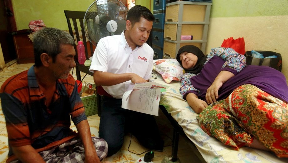KHAIRUL Faizi  (tengah) menerangkan Skim Peduli Kesihatan Untuk Kumpulan B40 kepada Maznah yang ditemani suaminya, Mohd Ali di Kampung Bagan Dalam.