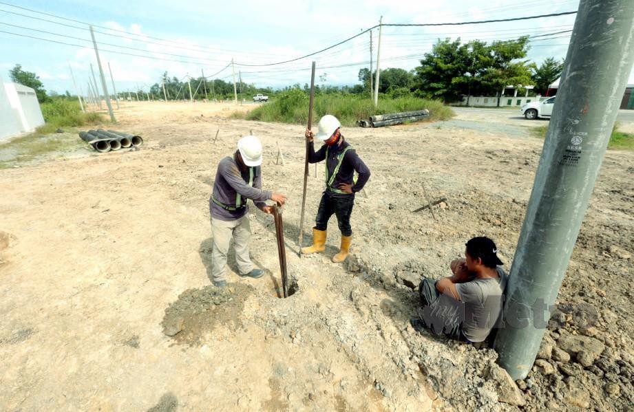 PEKERJA kontraktor memindahkan tiang elektrik bagi memberi laluan kerja penimbusan tanah untuk melebarkan jalan sedia ada yang terbabit dalam projek Lebuhraya Pan Borneo Sabah di kawasan Kimanis. FOTO EDMUND SAMUNTING.