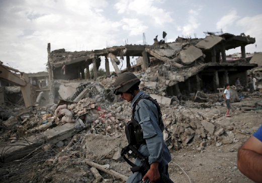 Polis Afghannistan berjalan di depan bangunan yang musnah akibat serangan bom terbesar di Kabul, Jumaat lalu. - Foto REUTERS