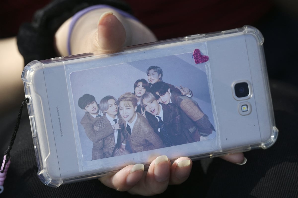 Seorang peminat BTS menunjukkan gambar kumpulan berkenaan yang dilekatkan pada telefon pintarnya. - FOTO AFP