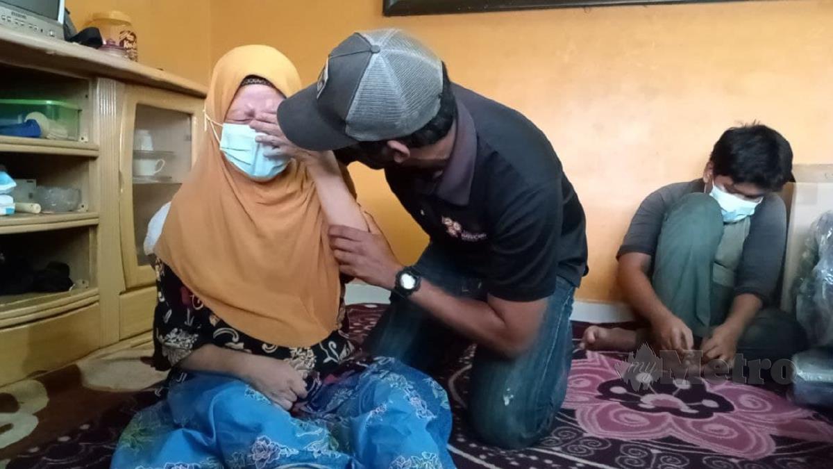 MAIMUN menangis ketika menceritakan keadaan keluarganya ditenangkan anaknya, Nik Mohd Mazrulhafendi. FOTO Omar Ahmad.