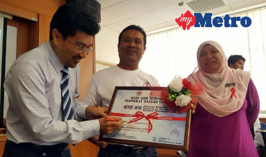 Dr Mohd Lutpiyudin (kiri sekali) diiringi Mohd Nasir (tengah) dan  Dr Azlina (kanan) menandatangani plak sebagai gimik perasmian Hari AIDS Sedunia Peringkat Daerah Langkawi di Klinik Kesihatan Kuah, sebentar tadi. FOTO Hamzah Osman
