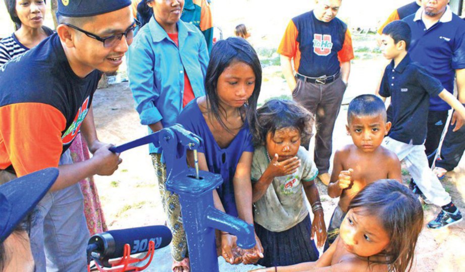 BASIRON (kiri) membantu seorang kanak-kanak yang ingin mendapatkan air telaga.