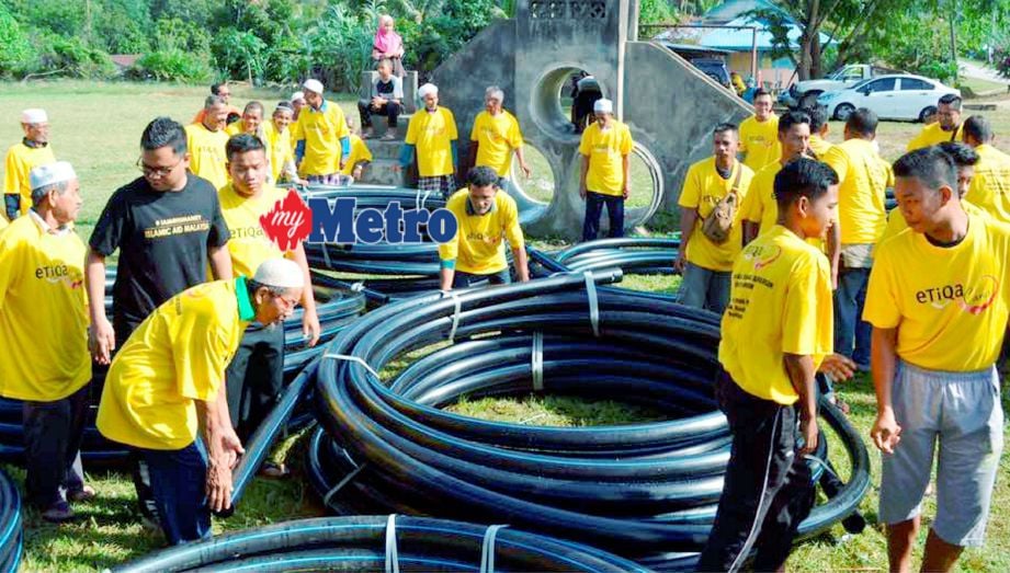 Sebahagian daripada sukarelawan membabitkan penduduk kampung, kakitangan Etiqa dan IAM bergotong-royong membantu mengangkat paip air pada Program Pembinaan Tandak Air Bersih Untuk Komuniti di Kampung Chuchoh Puteri, Kuala Krai. FOTO Siti Nadzirah Che Mud