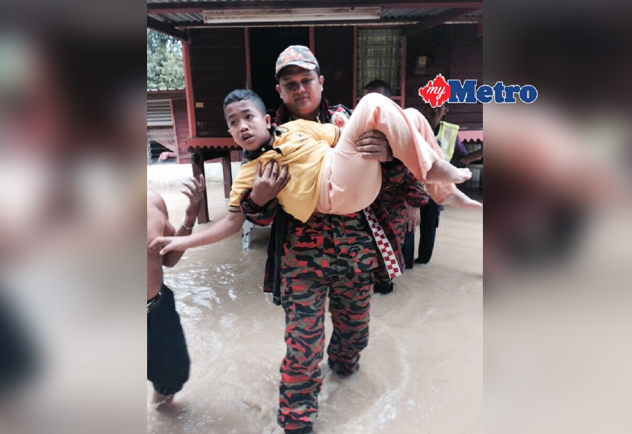Anggota bomba membantu memindahkan mangsa banjir kilat di Kampung Seri Menanti, Kuala Pilah. - Foto Ihsan Bomba