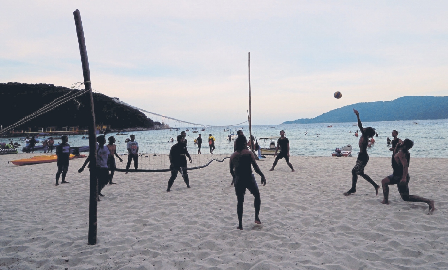 PENGUNJUNG beriadah dengan bermain bola tampar pada waktu petang di pesisir pantai Pulau Perhentian.