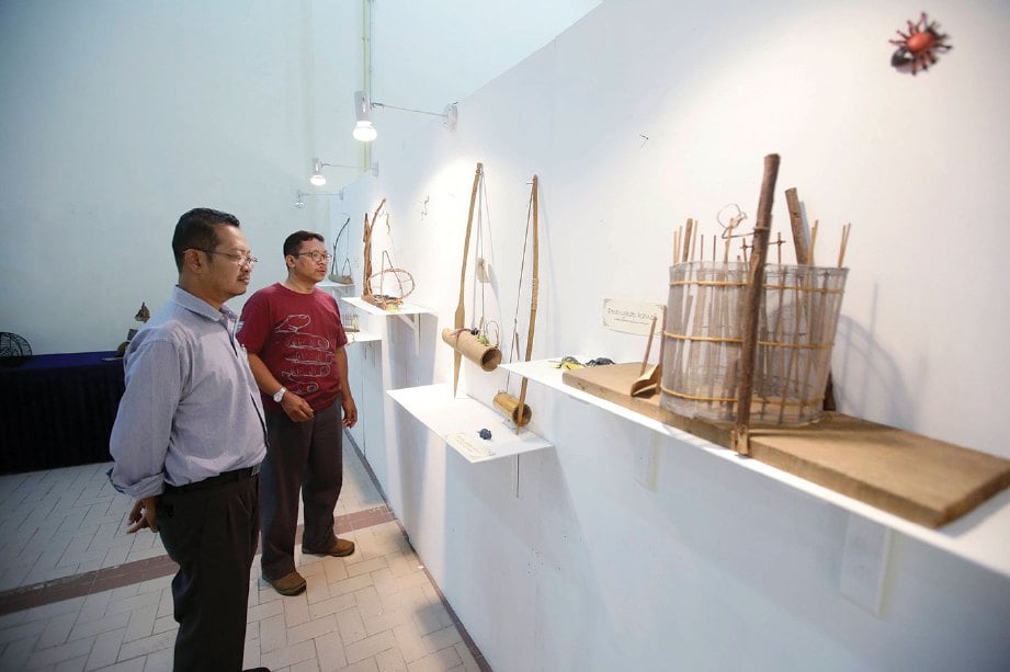 PENSYARAH kanan Jabatan Sosio Budaya Akademi Pengajian Melayu Dr Marzudi Md Yunus (kiri) melihat peralatan tradisional untuk ikhtiar hidup.