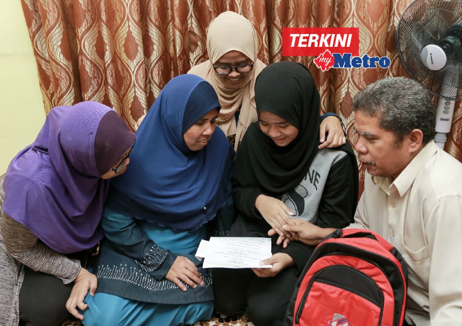 Aliyah Maisara (dua dari kanan) yang memperoleh keputusan UPSR cemerlang 6A pada 2016 membacakan surat tawaran kemasukan ke MRSM kepada ibu bapanya, Paizun  (dua dari kiri) dan Md Akir di Flat PPR Jelatek. Turut kelihatan kakaknya, Anis Rafidah Md Akir, 20, (kiri) dan Fatin Nur Syafiqah Md Akir, 22, (tengah). FOTO Asyraf Hamzah 