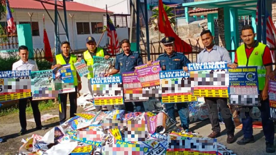 Penguat kuasa MDPT menunjukkan 430 iklan wang haram yang ditanggalkan dan disita di sekitar daerah Padang Terap. FOTO Ihsan MDPT