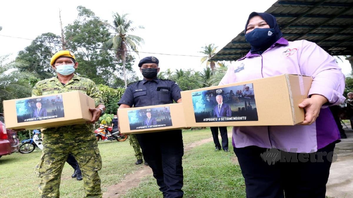 PASUKAN AMANITA, anggota polis, ATM dan Rela menyampaikan agihan kotak makanan kepada sebahagian penduduk kampung yang terjejas akibat pandemik Covid-19. FOTO Nik Abdullah Nik Omar.