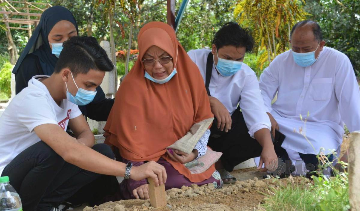 NORLIDA dan Md Tarmidi (kanan) bersama ahli keluarga di kubur Adik, kanak-kanak yang meninggal dunia dipercayai didera ibu kandung dan bapa tirinya di Tanah Perkuburan Islam Padang Lebar, Simpang Bekoh, Jasin. FOTO Amir Mamat