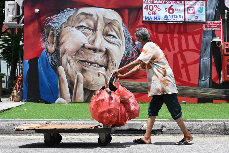 SEORANG warga emas memakai pelitup muka menolak troli melewati mural di Singapura. FOTO AFP