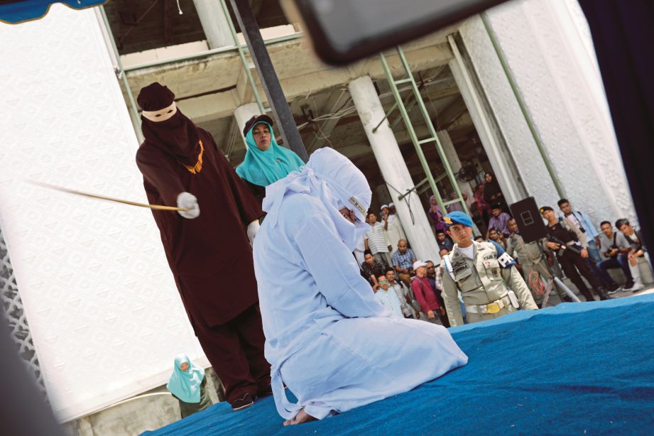 SEORANG wanita antara 11 pesalah yang dihukum sebat di luar sebuah masjid kerana melakukan maksiat di Aceh. FOTO: AFP