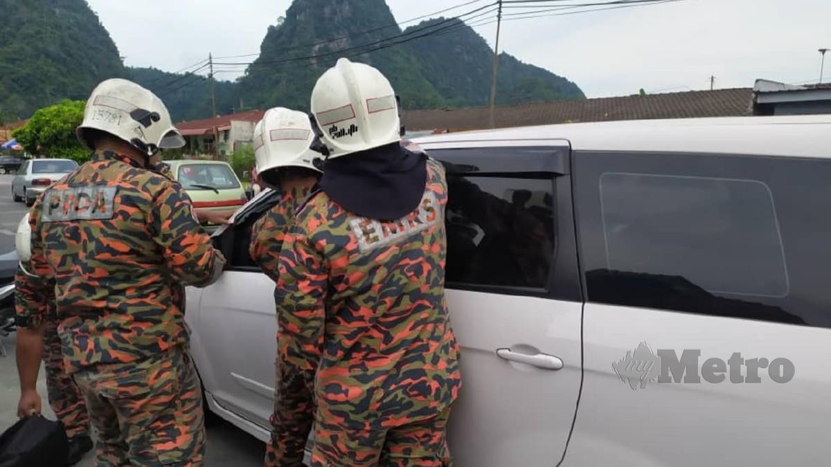 Anggota bomba cuba membuka pintu kenderaan untuk menyelamatkan tiga beradik yang terkunci di Taman Perpaduan, Ipoh hari ini. Foto Ihsan JBPM  