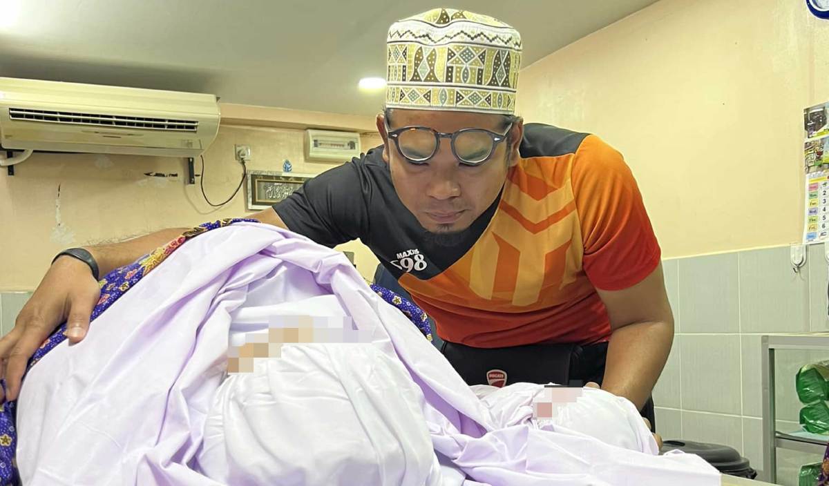 SUAMI Nor Ezaty memeluk jenazah isterinya buat kali terakhir.  FOTO Facebook Mr Wan Cai Official