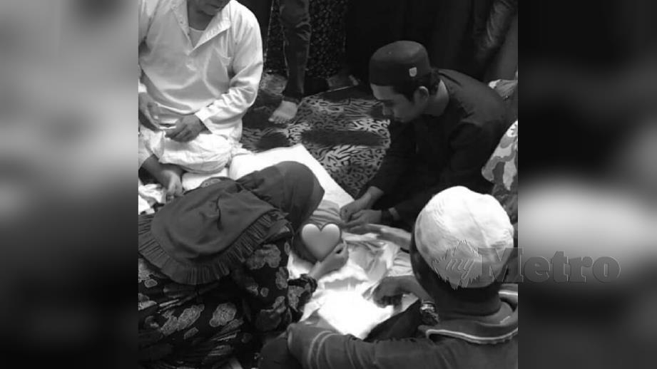 Muhammad Ikhwan (kanan) dan Nur Dalila Aqilah memberi ciuman terakhir kepada anak tunggal mereka. FOTO Ihsan Nur Dalila Aqilah Mohd Yusof