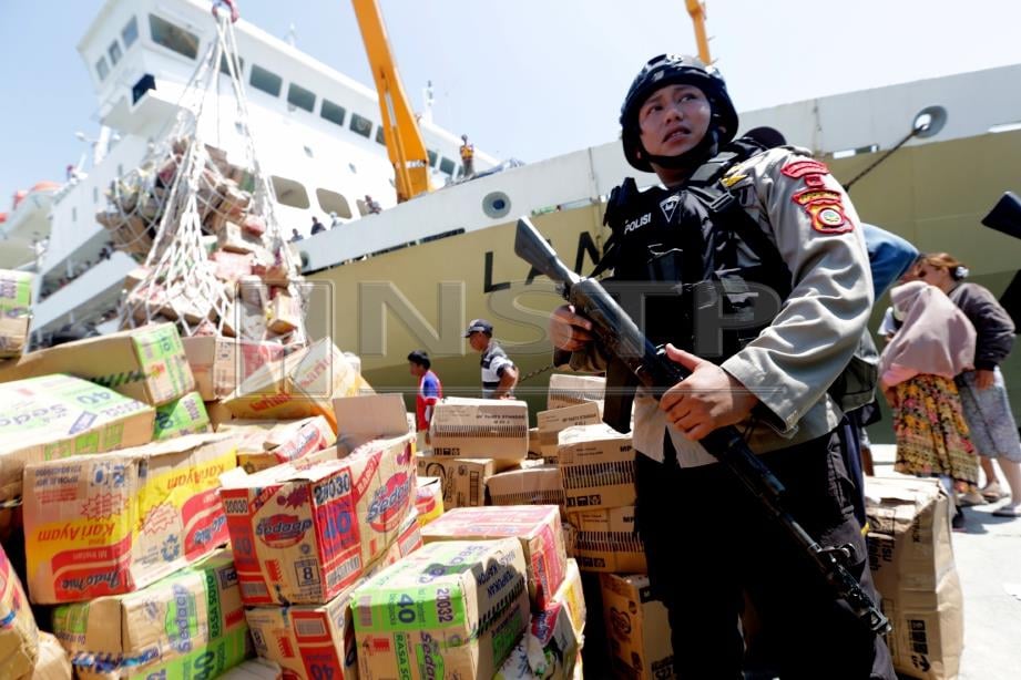 ANGGOTA polis mengawal makanan sebelum diedarkan kepada mangsa tsunami. FOTO/AFP  