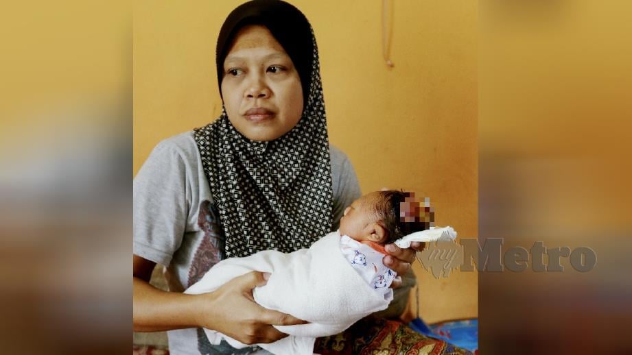 GAMBAR kenangan Norwati memangku Nur Annissa ketika ditemui di Kampung Kuala Linggi, Alor Gajah, baru-baru ini. FOTO Khairunisah Lokman. 