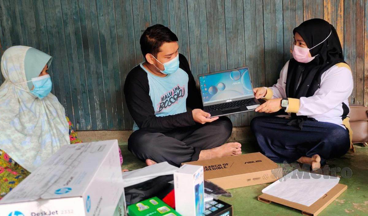 MOHAMMAD Daniel Muiz'zudin Shah menerima komputer riba daripada wakil Yayasan Raja Shamri (YRS) , Tuan Zaimah (kanan) sambil diperhatiakan neneknya, Siti Esah di rumahnya di Kampung Gual Mekong, Bukit Tandak. FOTO Syaherah Mustafa