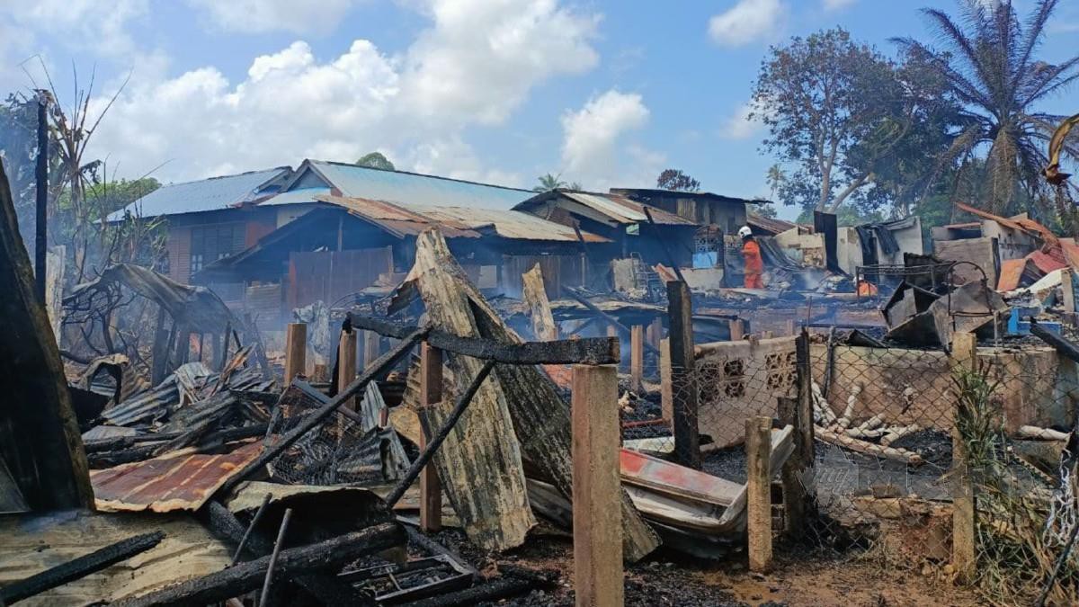 ANGGOTA bomba sedang memadamkan kebakaran membabitkan tiga rumah di Kampung Laut, Tumpat, hari ini, FOTO SITI ROHANA IDRIS