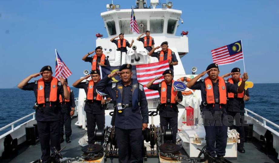 MUHD Nur Syam Asmawie (tengah) bersama pegawai dan anggota APMM membuat persiapan mengibarkan Jalur Gemilang di Kapal KM Tok Bali. FOTO NIK ABDULLAH NIK OMAR
