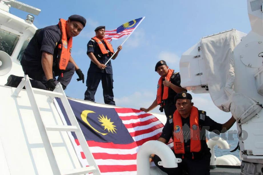 PEGAWAI dan anggota APMM Kelantan membuat persiapan memasang Jalur Gemilang bagi menyemarakkan sambutan Hari Kemerdekaan ke-63 ketika menaiki kapal KM Tok Bali. FOTO NIK ABDULLAH NIK OMAR