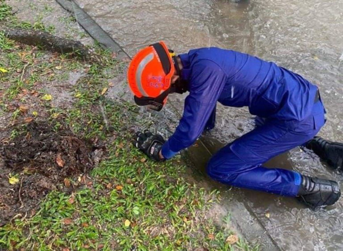 ANGGOTA APM berusaha membersihkan lubang saluran air dan longkang yang tersumbat akibat sampah di Putrajaya tadi.