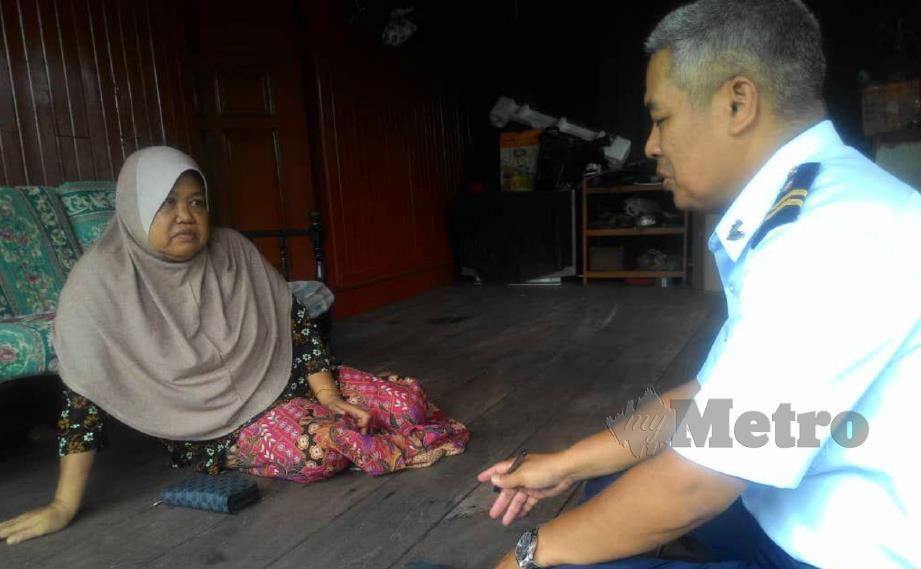 RUHAYATI (kiri) mendengar penjelasan mengenai operasi mencari suaminya daripada Abdul Idrus ketika mengunjungi rumahnya di Kampung Gong Pak Jin, Mengabang Telipot, Kuala Nerus. FOTO Zaid Salim. 