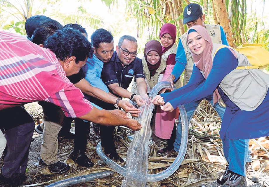 DR MUSA (lima kanan) dan artis Diana Amir (kanan) selaku Ikon IRM bersama penduduk kampung mencuba air bersih daripada Projek Aqua.