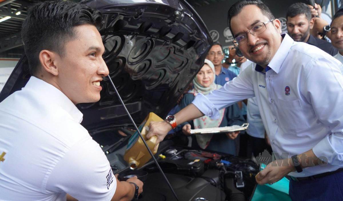 ASYRAF Wajdi (kanan) menuang minyak enjin ke dalam enjin sebuah kereta di sebuah cawangan pusat servis kenderaan semasa Program Pembangunan Usahawan Automotif MARA-Petronas di Titi Chai, Utan Aji, Kangar. FOTO Aizat Sharif