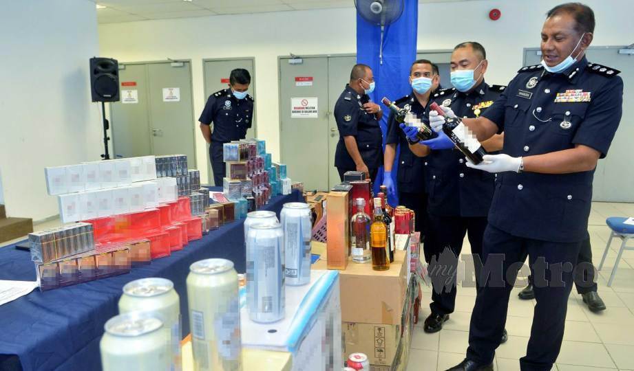 BAHARUDIN (kanan) menunjukkan antara rokok seludup serta minuman keras pelbagai jenama yang dirampas pada sidang media di Ibu Pejabat Polis Daerah Shah Alam. FOTO Faiz Anuar