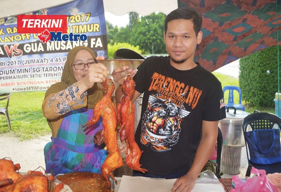 Mohd Ebbie bersama ibunya menunjukkan arnab panggang dijual di Bazar Ramadan Kampung Guntung Luar yang kini tular di laman sosial. FOTO NURUL FATIHAH SULAINI