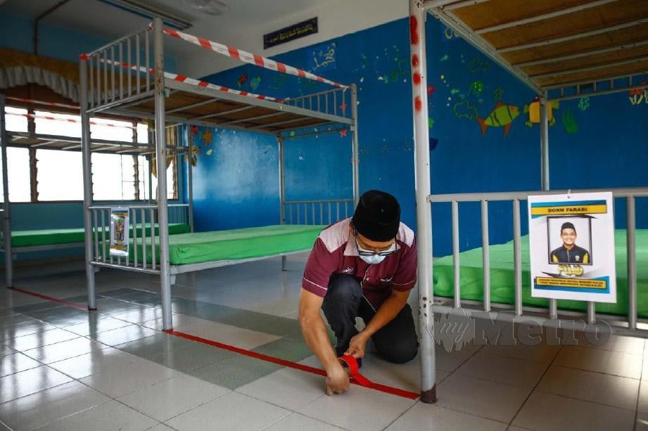 Guru, Mohd Noruddin Rohmat, 33, menampal pita pelekat penjarakan sosial di asrama bilik lelaki di Sekolah Menengah Kebangsaan King George V (KGV), Seremban. FOTO arkib NSTP 