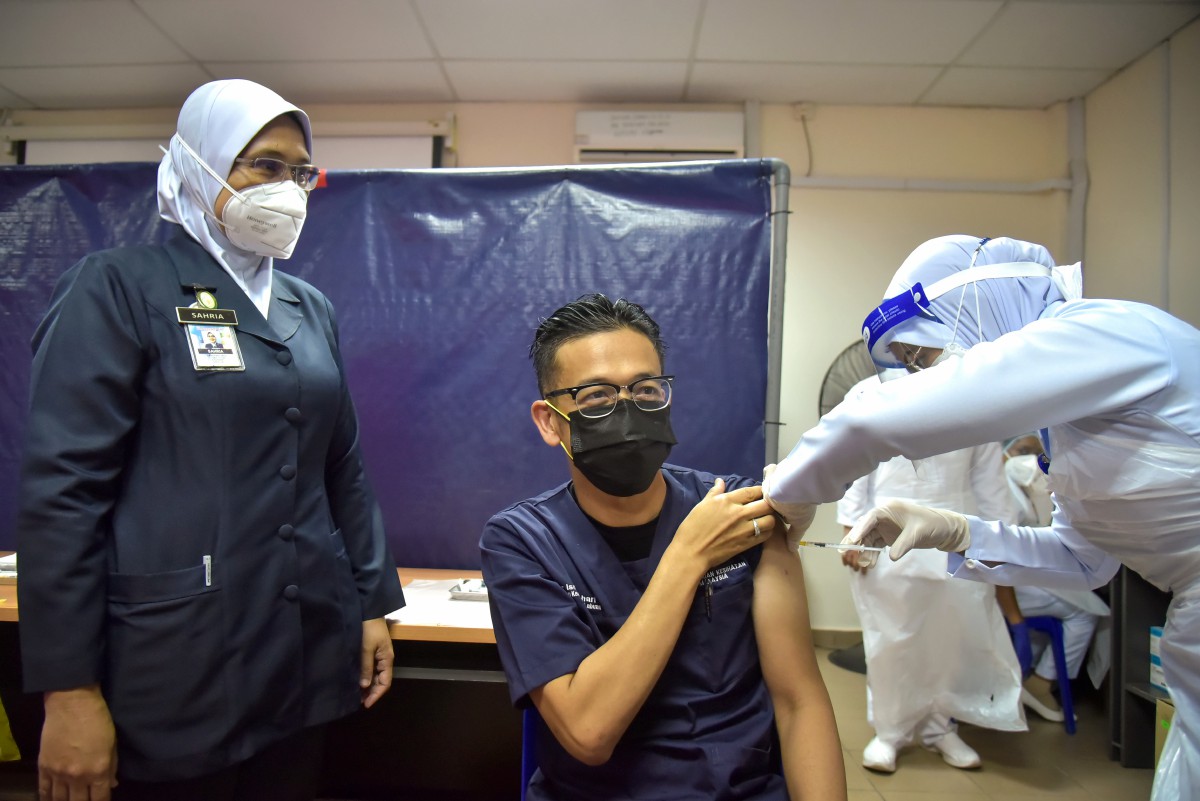 DR ISMUNI (tengah) menerima suntikan dos penggalak vaksin COVID-19 daripada vaksinator kesihatan di Pusat Pemberian Vaksin Klinik Kesihatan Membedai hari ini. FOTO BERNAMA