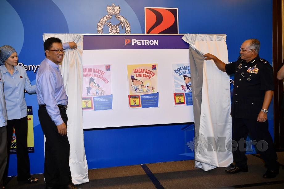 ZAINAL Abidin (kanan) melancarkan poster inisiatif kesedaran keselamatan GTSP Petron Malaysia sempena Majlis Penyampaian Surat Penghargaan PDRM kepada Pengusaha Stesen. FOTO BERNAMA