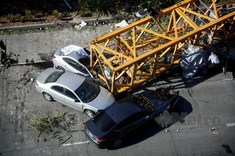 KEADAAN kren yang tumbang dan menghempap enam kenderaan. -Foto Reuters