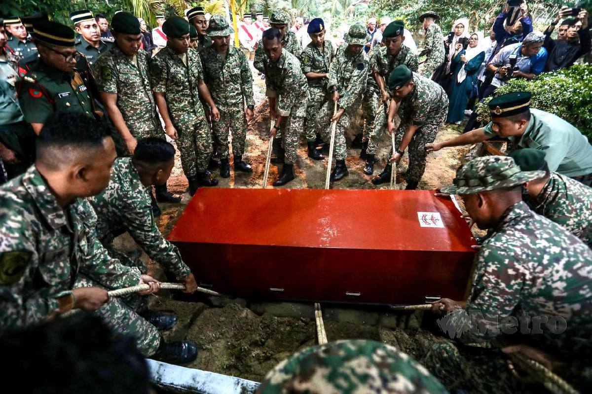 ANGGOTA ATM membantu proses pengebumian jenazah Sarjan Rozali yang maut dalam kemalangan untuk dikebumikan di Tanah Perkuburan Gong Bayor, Besut, hari ini. FOTO Ghazali Kori