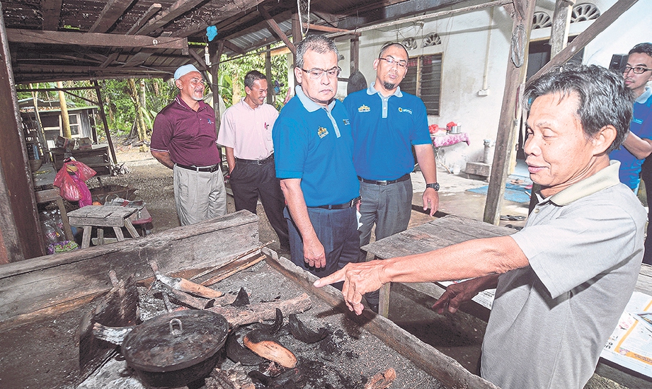 PENERIMA bantuan zakat, Mohd Supir Ibrahim (kanan) menunjukkan perkakasan membuat baulu gulung yang diterima menerusi skim bantuan modal LZS kepada Hussin.