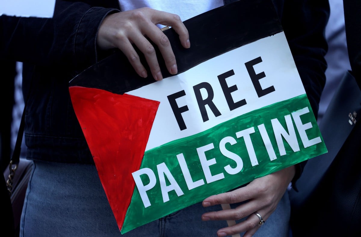 PLAKAD Free Palestine dipegang orang ramai yang berhimpun di Grant Park, Chicago dan berarak ke konsulat Isreal sebagai membantah serangan udara ke atas Palestin pada Rabu. FOTO AFP.