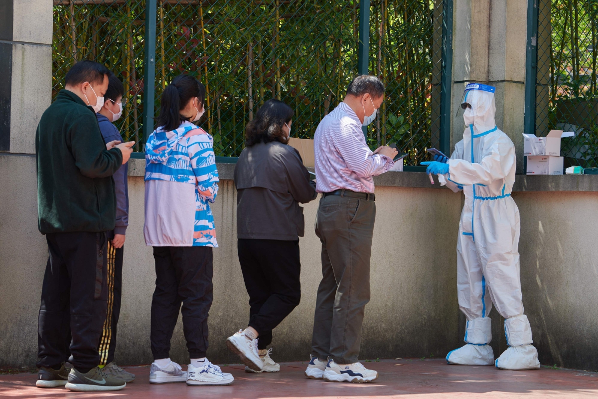 SUKARELAWAN komuniti membantu penduduk yang mahu menjalani ujian saringan Covid-19 di daerah Pudong, Shanghai. FOTO AFP 