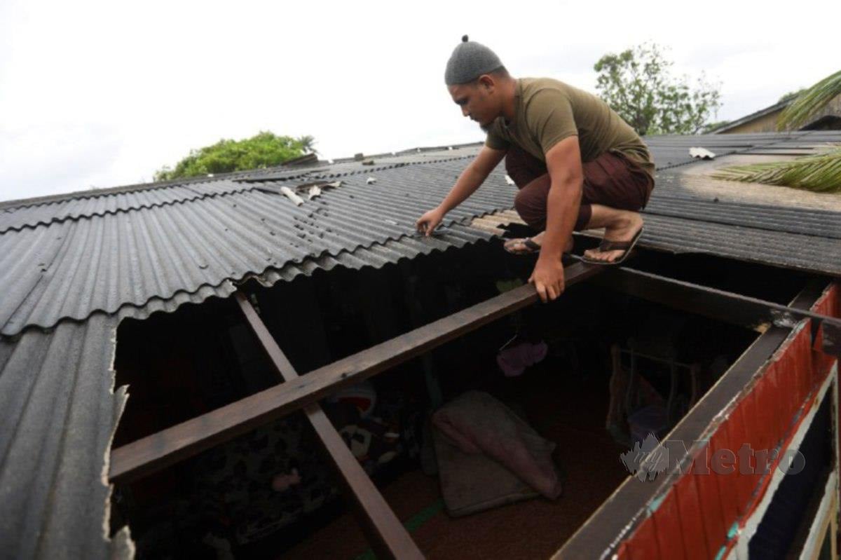 MOHAMAD Fareezuan membaiki bumbung rumah yang rosak selepas dibadai ribut di Kampung Tanjung Gelam. FOTO Ghazali Kori