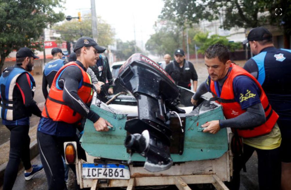 DUA atlet kanu Brazil, Evaldo Becker dan Piedro Tuchtenhagen sedang mengangkat bot untuk membantu mangsa banjir. FOTO Agensi