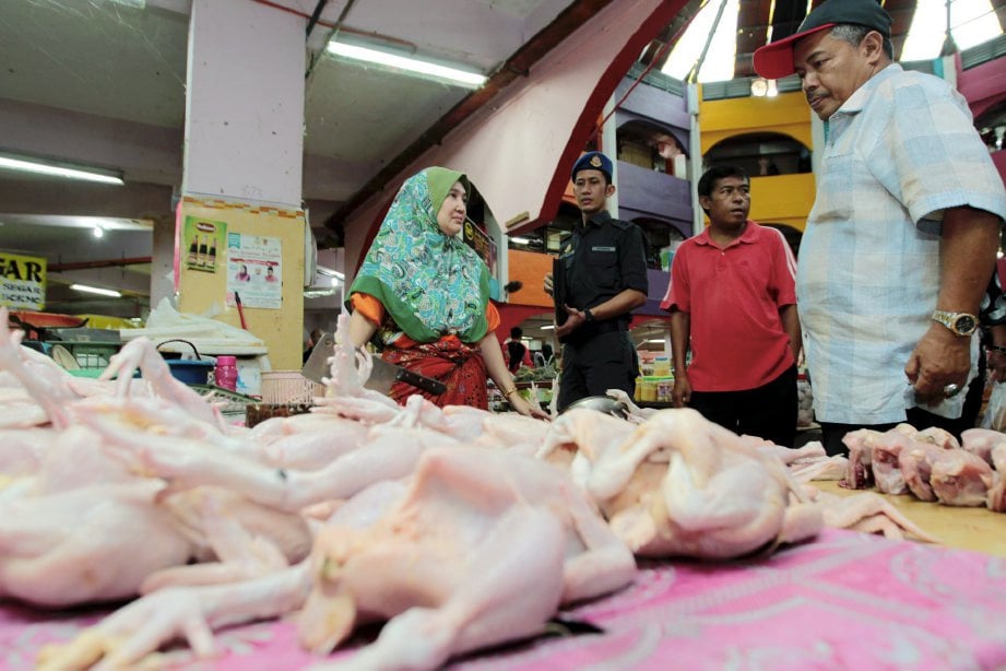 Pengarah KPDNKK Kelantan, Datuk Abdul Ghani Harun (kanan) bersama pegawai penguatkuasa KPDNKK bertanyakan sesuatu kepada peniaga ayam di Pasar Siti Khadijah di Kota Bharu. FOTO Syamsi Suhaimi