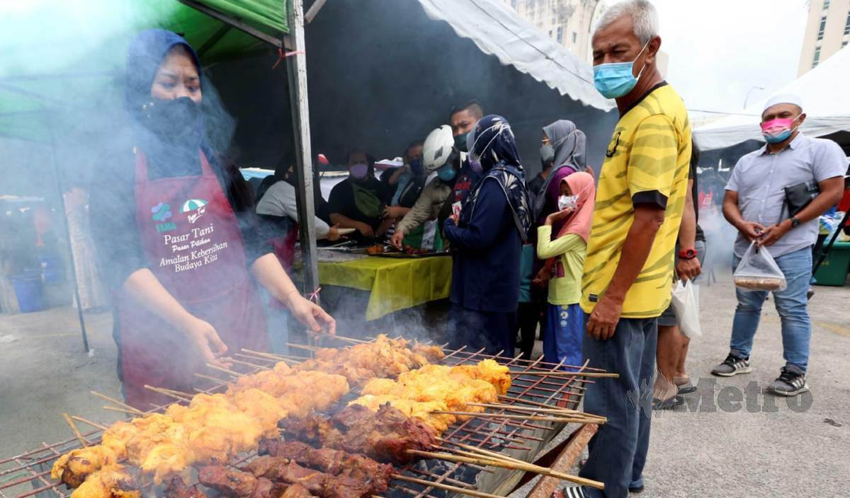 PENIAGA ayam percik sibuk membakar ayam percik yang ditempah pelanggannya di bazar perkarangan Stadium Sultan Muhammad IV. FOTO Nik Abdullah Nik Omar